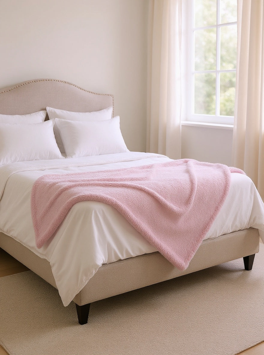 Couverture polaire rose au pied du lit